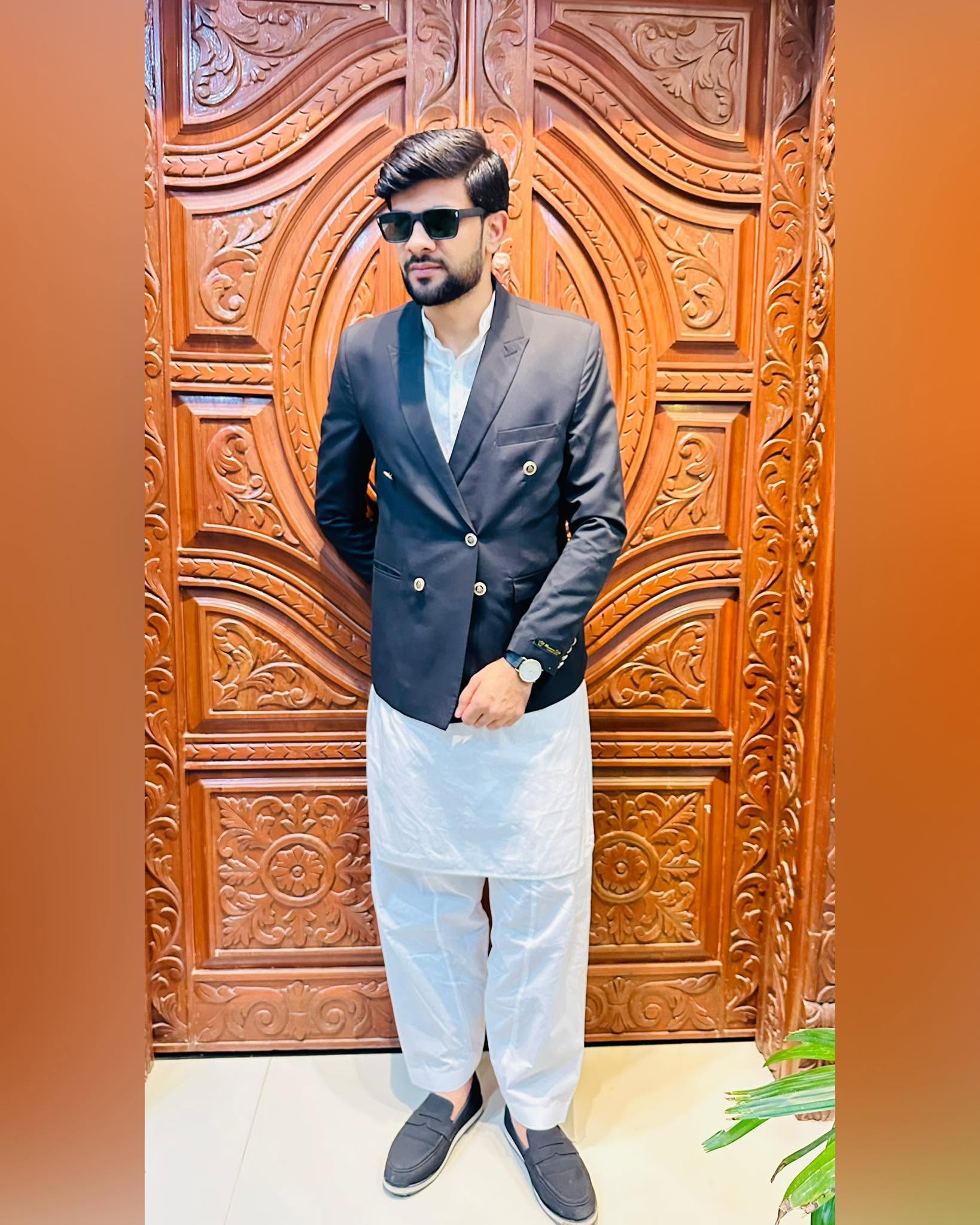 Muhammad Muzamel Iqbal wearing a charcoal blazer and sunglasses, pictured waist-up